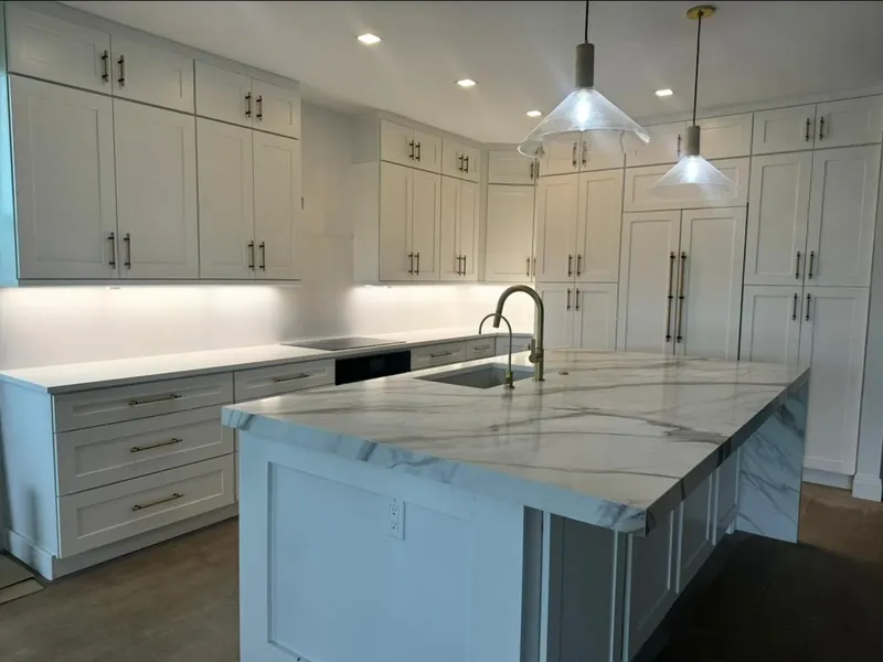 White kitchen with marble-look waterfall island and pendant lights